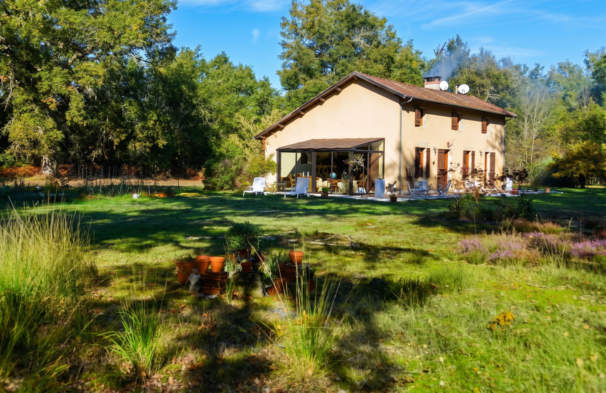 Une maison à deux étages dotée d’un patio, entourée d’une pelouse bien entretenue et d’arbres.