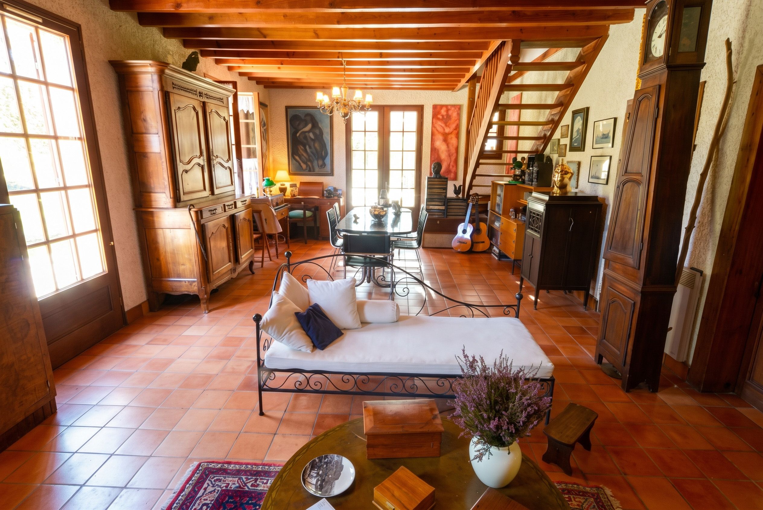 A cozy living room with a sofa, dining table, and a staircase leading to an upper level.