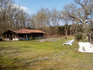 A rustic wooden structure with a tiled roof, surrounded by a grassy field and trees. - Homerez - Festive House in Callen (Callen)