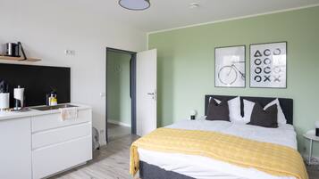 A modern bedroom with a bed, bedside tables, a wardrobe, and a door leading to another room.