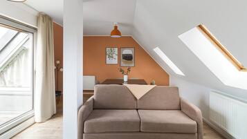 Una sala moderna con un sofá, una mesa de comedor y una lámpara colgante.