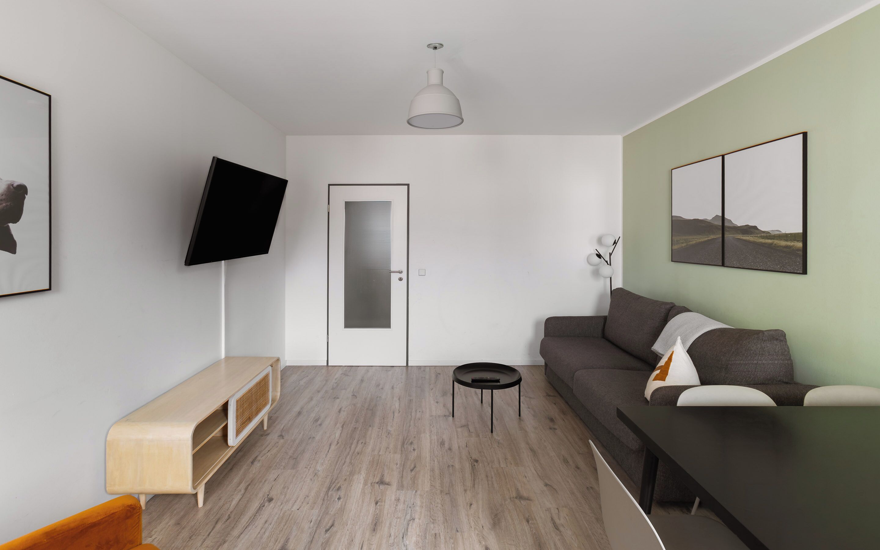 Una sala moderna con una televisión de pantalla plana, un sofá, una mesa de centro y una puerta.