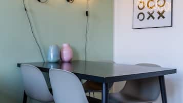 Un comedor con una mesa y cuatro sillas, un letrero de neón que dice "SO SUITE" y una obra de arte abstracta enmarcada en la pared.