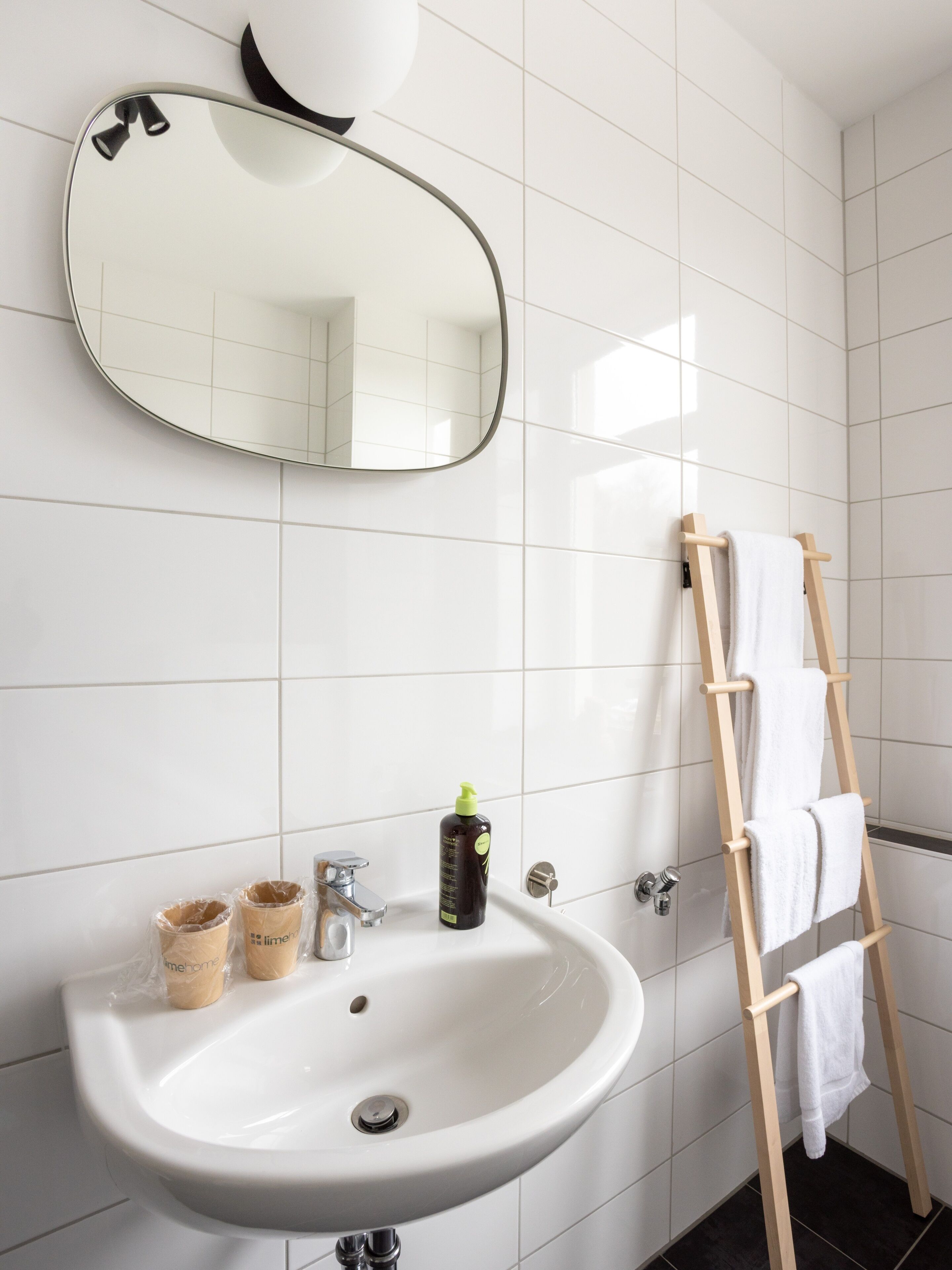 A bathroom with a white sink, a mirror, a towel rack, and toiletries.