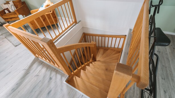 A wooden staircase with a handrail, leading to a landing.