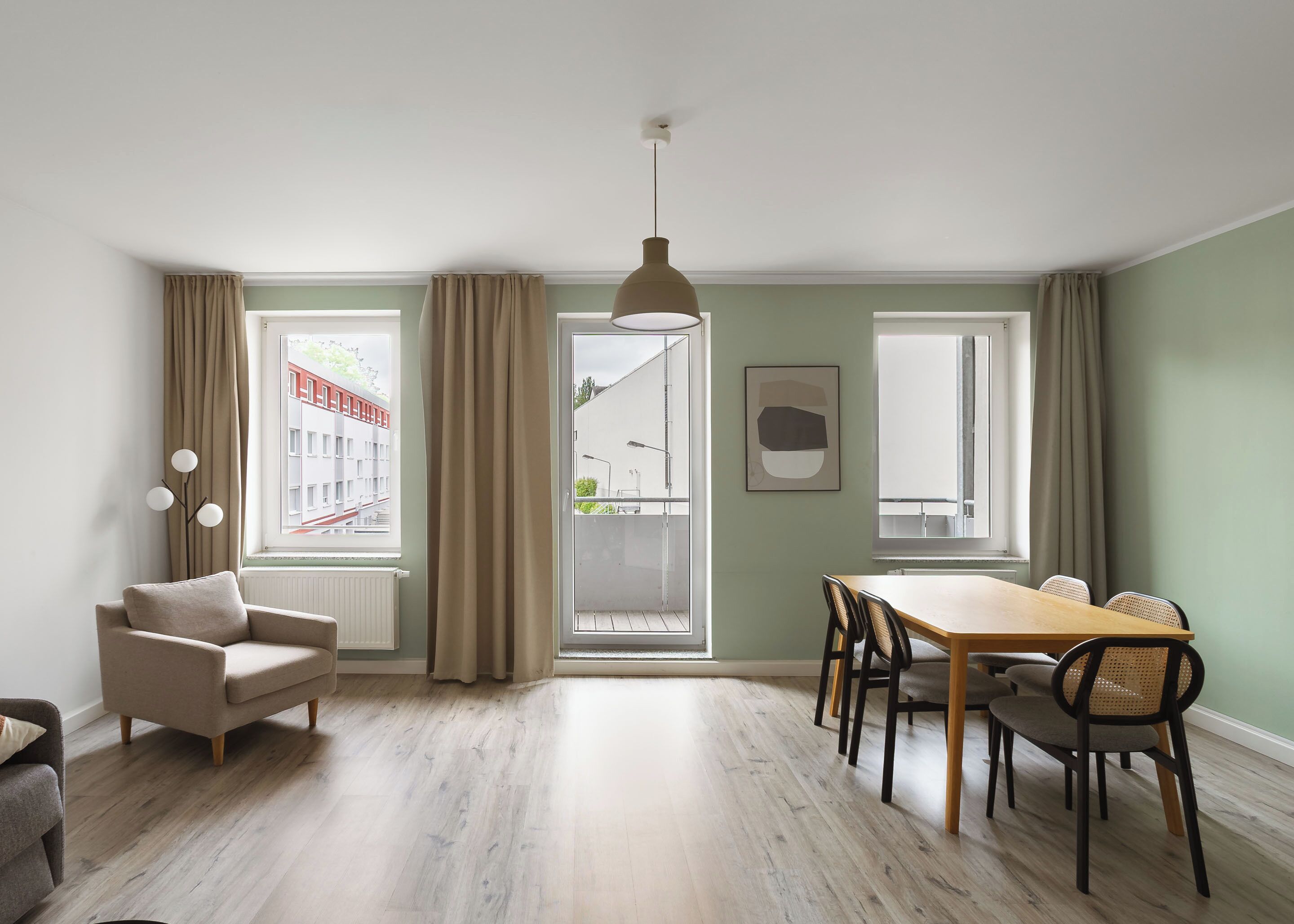 A modern living room with a dining area, large windows, and a view of the outside.