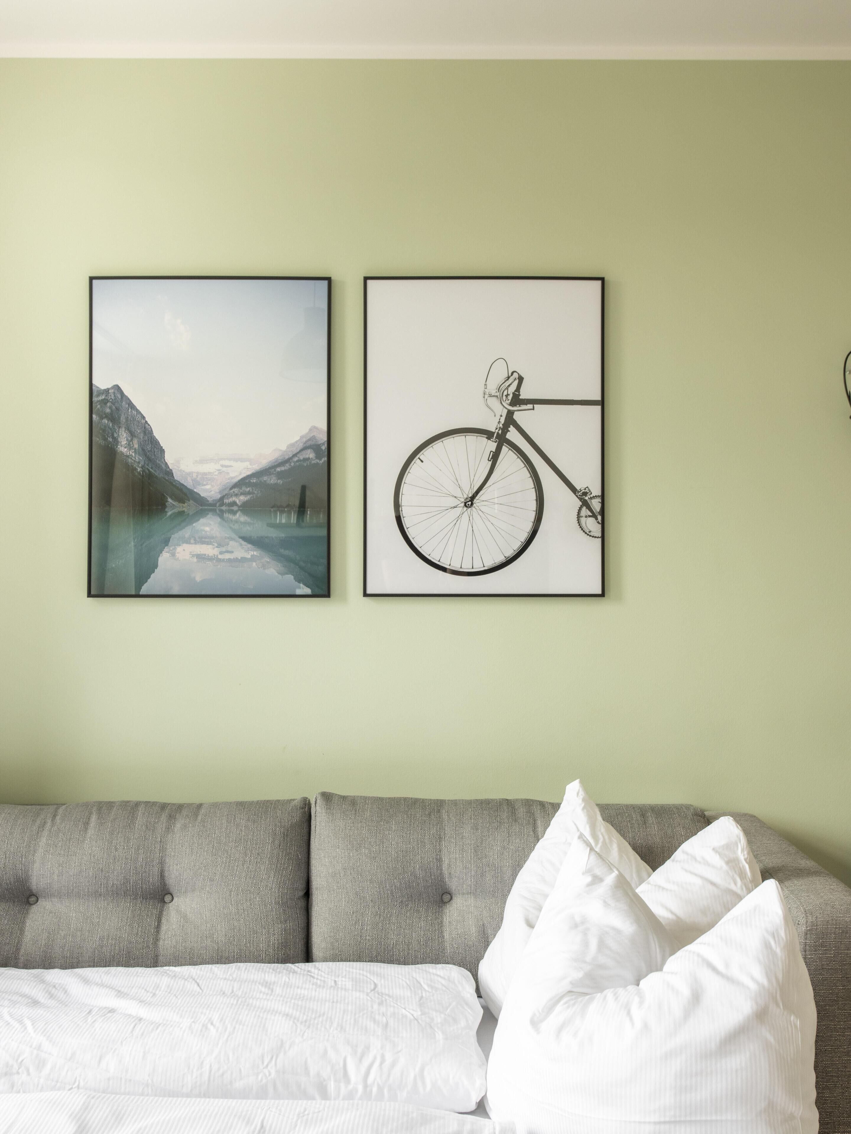 Una habitación con un sofá gris, almohadas blancas y dos cuadros en la pared.