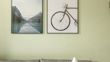 Una habitación con un sofá gris, almohadas blancas y dos cuadros en la pared.