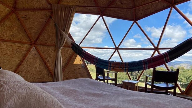 Een gezellige kamer met een bed, een hangmat en uitzicht op de natuur.