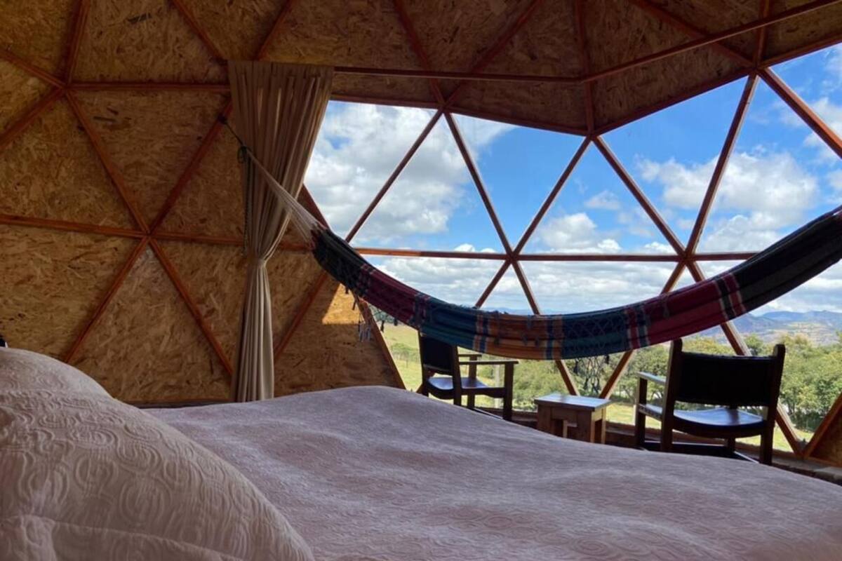 Een gezellige kamer met een bed, een hangmat en uitzicht op de natuur.