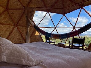 Een gezellige kamer met een bed, een hangmat en uitzicht op de natuur.