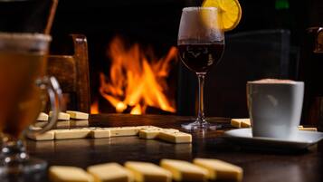 A bar setting with a glass of red wine, a white cup, and dominoes on a table.