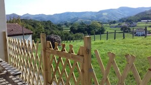 A wooden fence with a view of a green landscape and distant mountains.