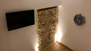 Un rincón de una habitación con pared de piedra, un televisor de pantalla plana montado en la pared y una placa decorativa.