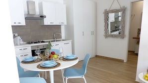Una cocina moderna con armarios blancos, una mesa de comedor con platos azules y sillas azul claro.