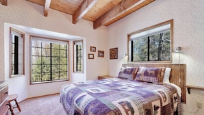 A bedroom with a large bed, two windows, a dresser, and a nightstand. - Wodehouse #1057 (Big Bear Lake)