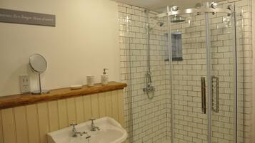 Un baño con ducha envuelta en vidrio, tocador de madera con espejo y lavamanos blanco.