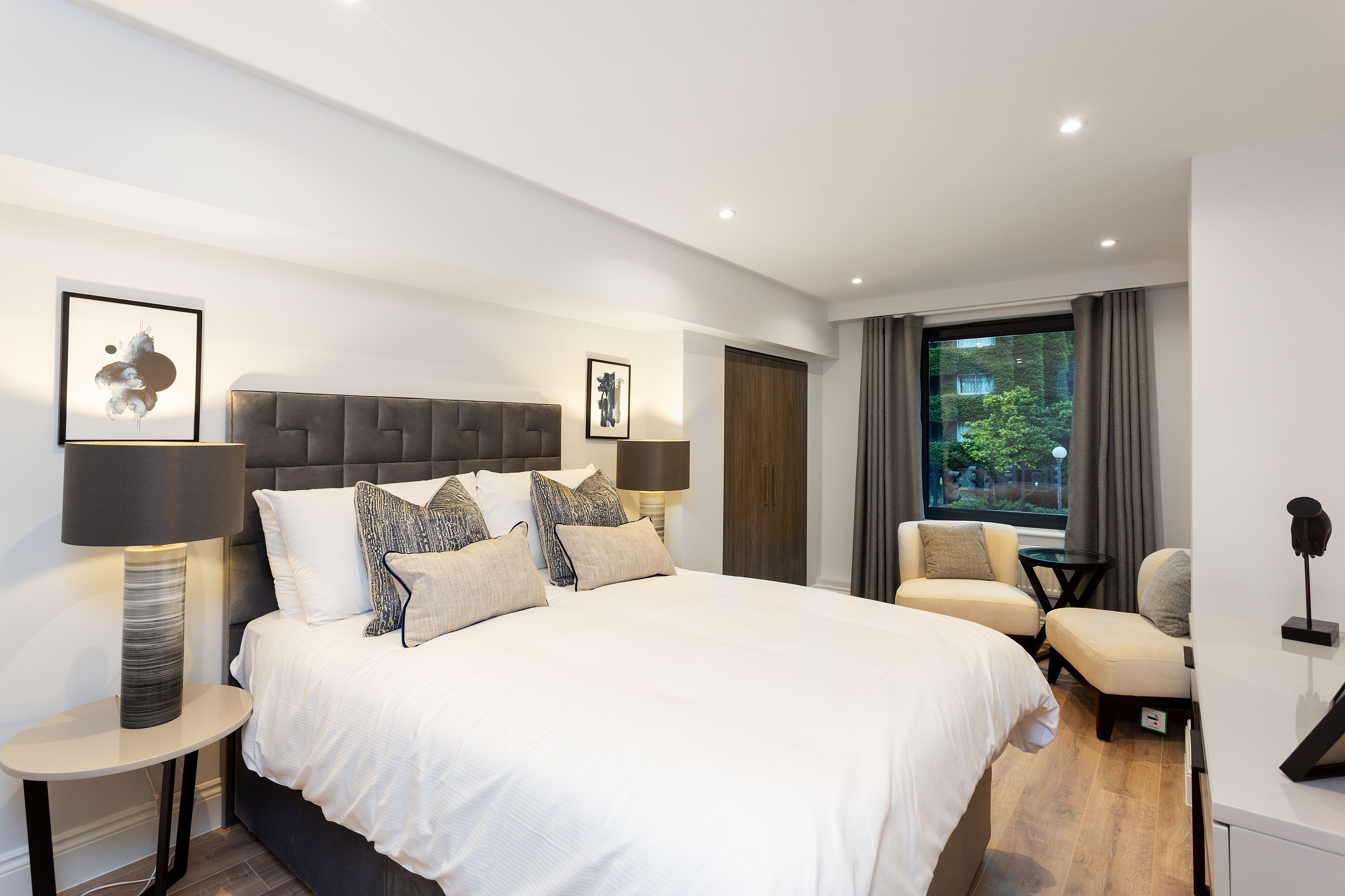 Une chambre d’hôtel moderne avec un grand lit, deux tables de chevet, un bureau et une chaise.