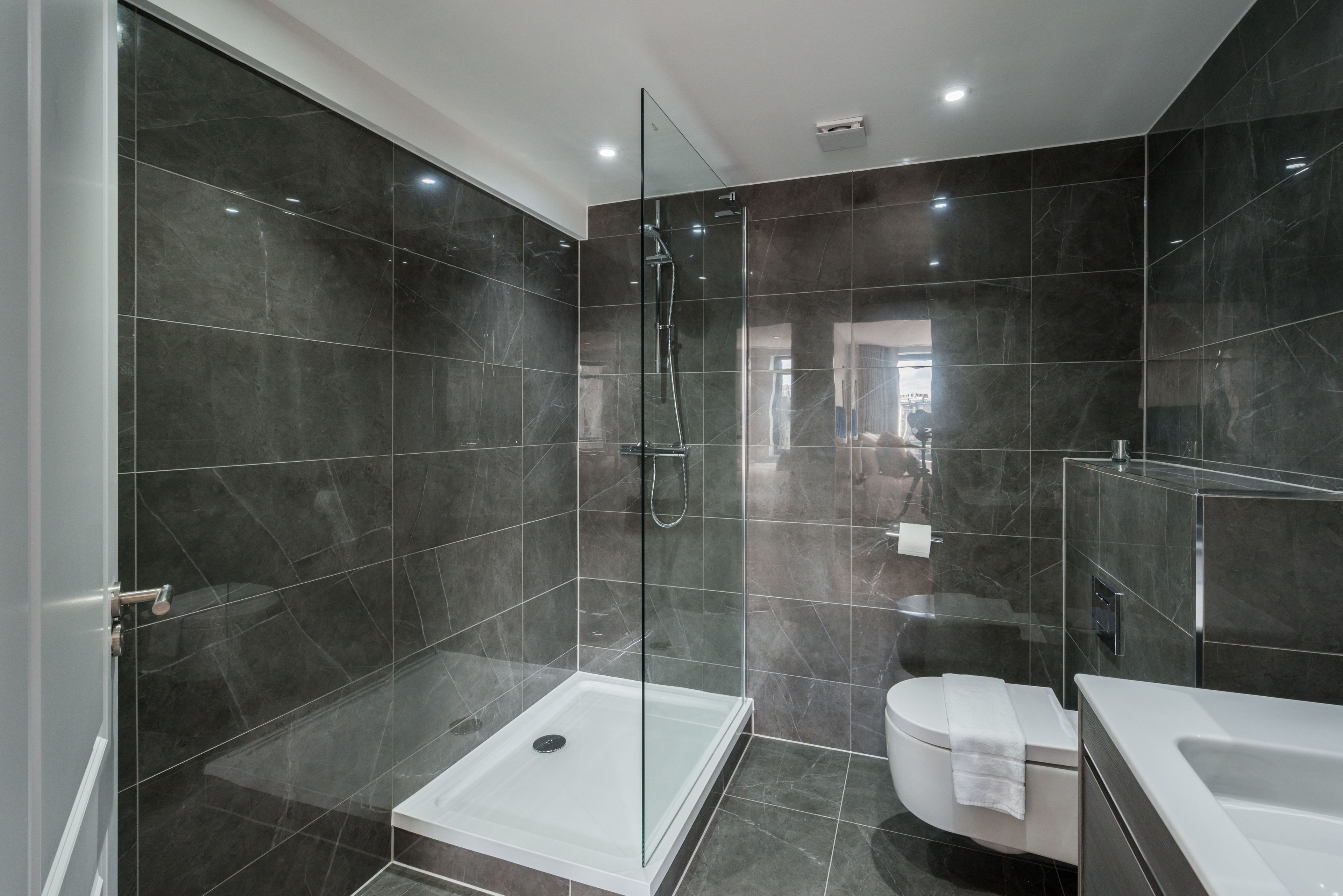 A modern bathroom with a glass-enclosed shower, a white toilet, and a large bathtub.