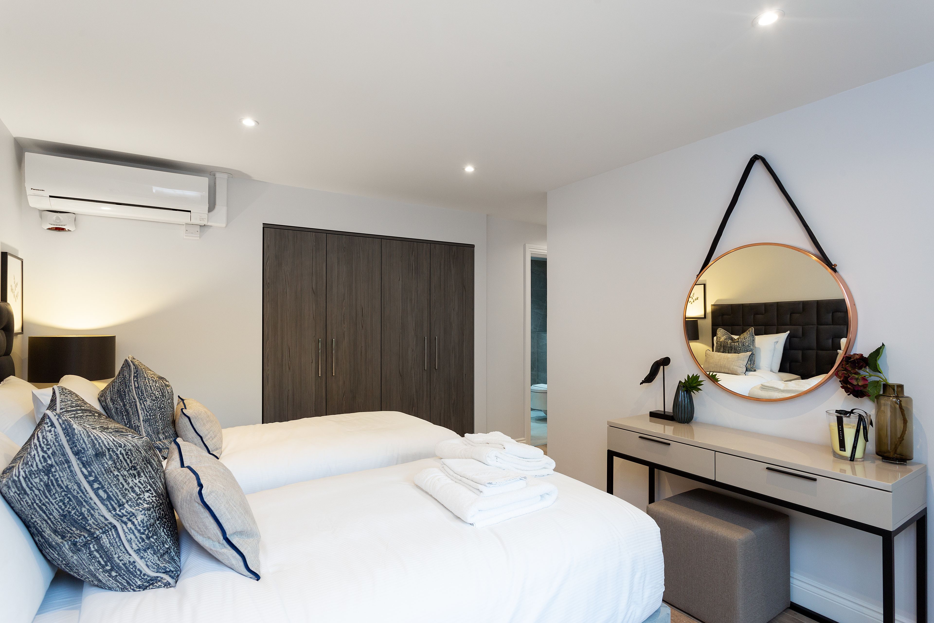 A modern hotel room with a bed, bedside table, and a large mirror.
