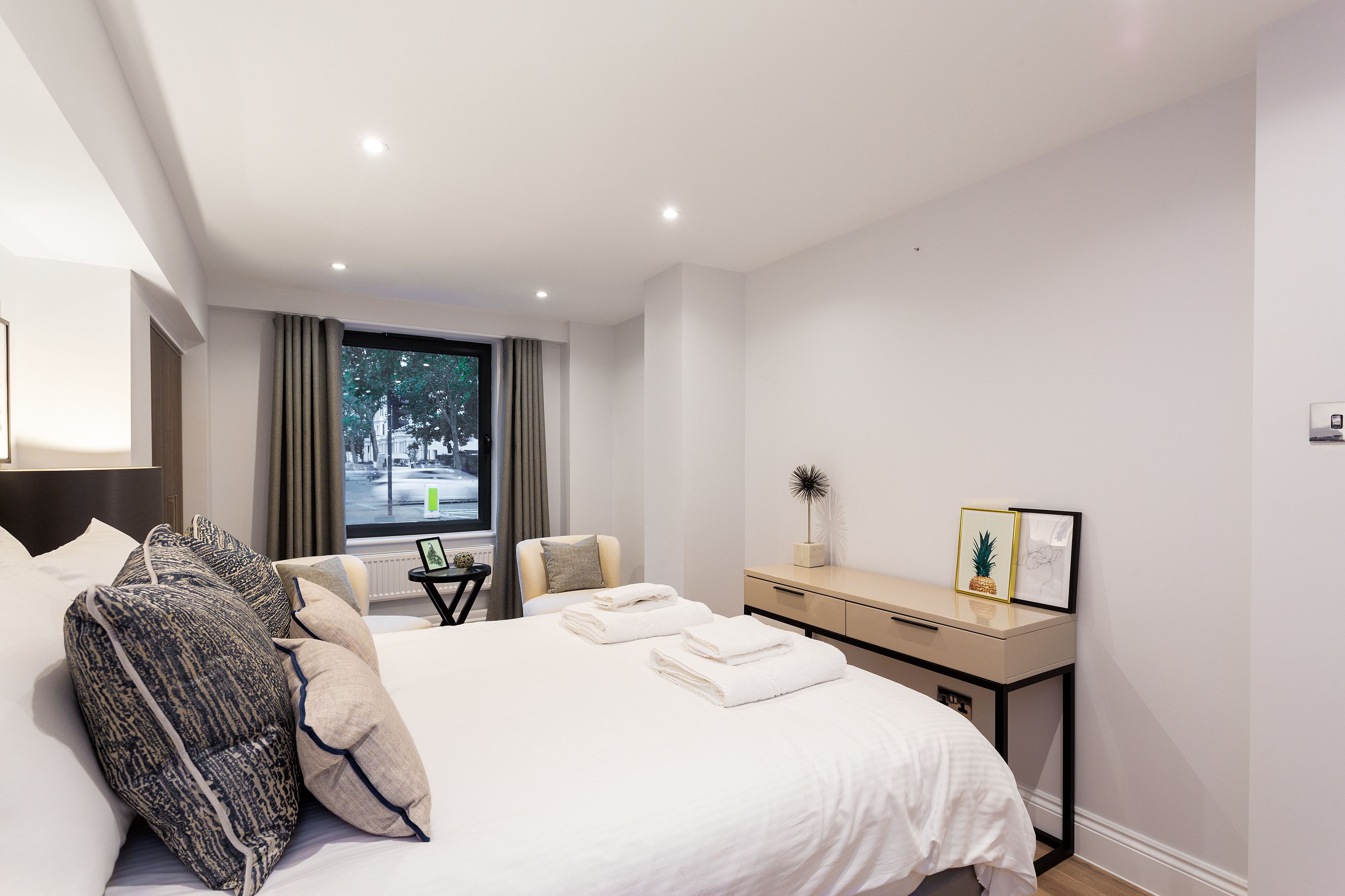 Une chambre d’hôtel moderne, avec un lit bien fait, un bureau et une vue sur la ville par la fenêtre.