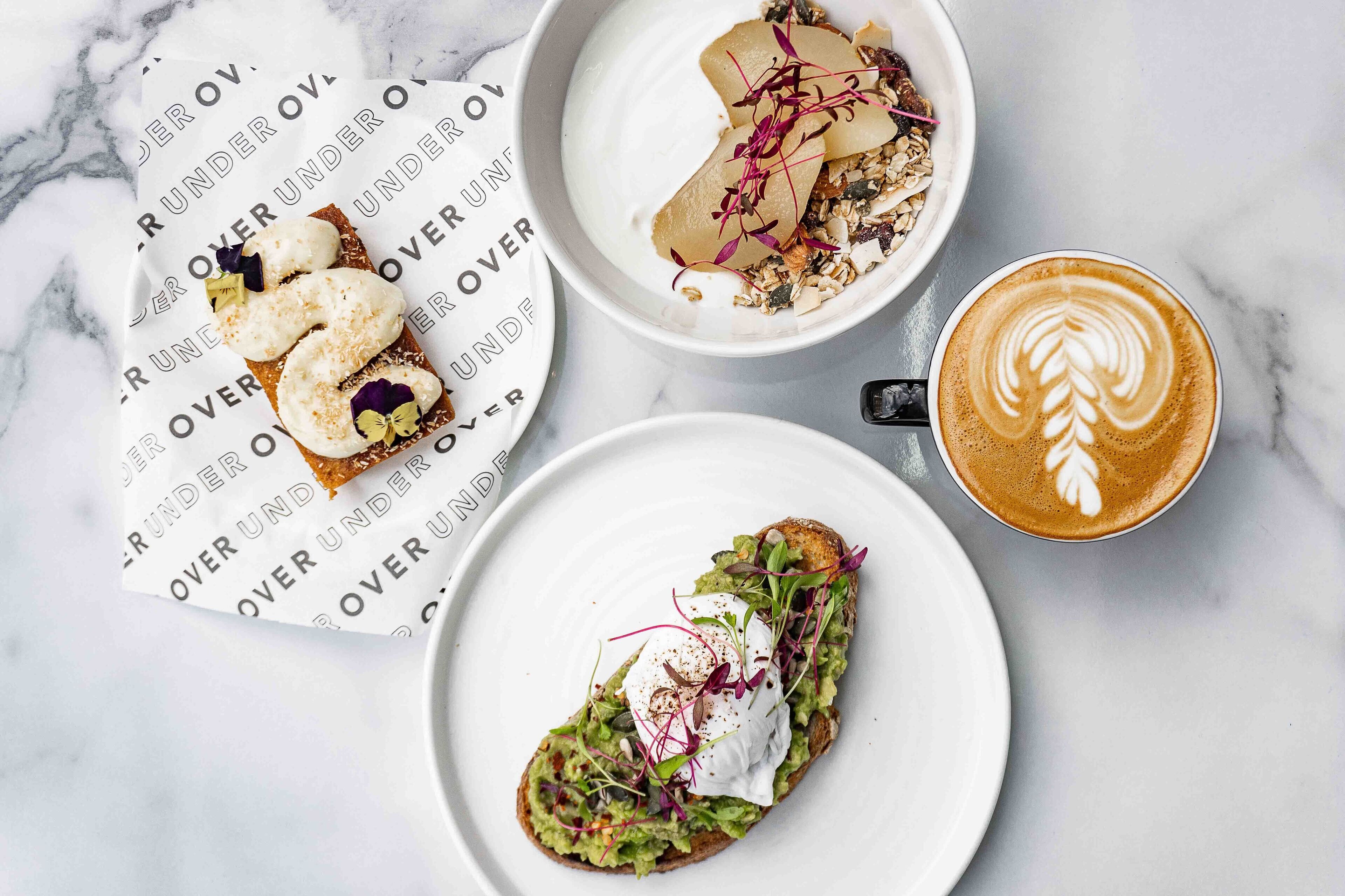 A table with a cup of coffee, two plates of food, and a menu.