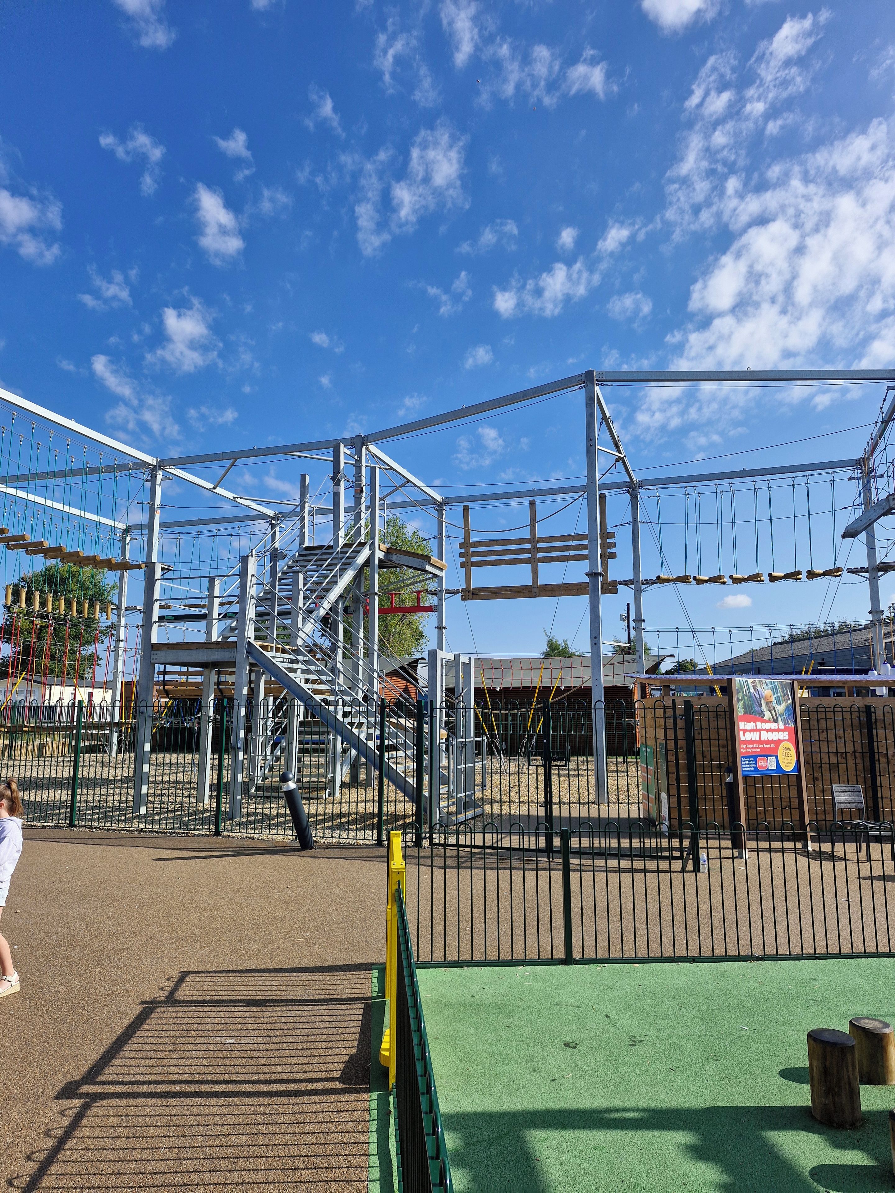 A playground with a metal climbing structure and a fenced area.