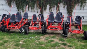 A row of red lawn tractors with black seats parked in a grassy area. - Highfield Grange Holiday Park
3 Bed Sleeps 8
 (Clacton-on-Sea)