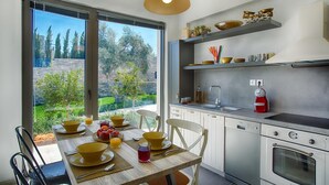 Een moderne keuken met een groot raam, een ontbijtgedekte eettafel en een ingebouwde oven.