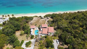 A coastal property with a swimming pool, a beach, and dense greenery. - Joie de Vivre (4 bedrooms) - Beachfront Baie Rouge villa with pool, Terres Basses, St. Martin (Les Terres Basses)