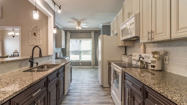 A kitchen with granite countertops, dark wooden cabinets, a double sink, a refrigerator, and a microwave. - FAMILY RETREAT/ PET FRIENDLY NEAR MILITARY BEACHES AND BASES (Jacksonville)