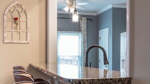 A modern kitchen with a bar area, a decorative window with a rose, and a ceiling fan. - FAMILY RETREAT/ PET FRIENDLY NEAR MILITARY BEACHES AND BASES (Jacksonville)