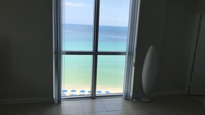 Una habitación con un amplio ventanal corredero que da a vista de playa.