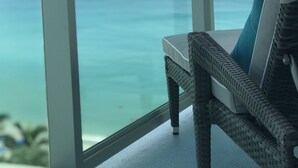 Un balcón con una silla de mimbre y vista al océano.