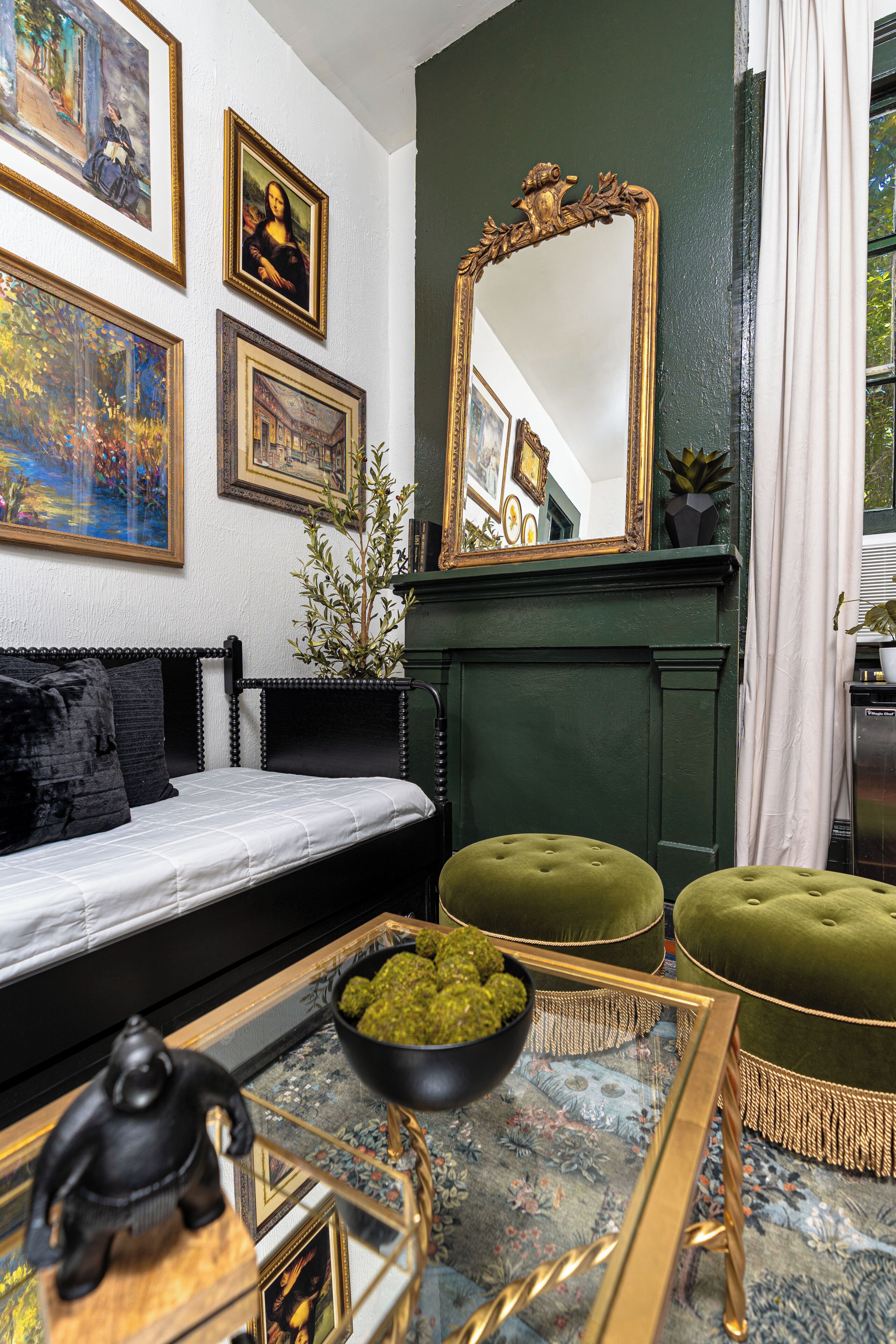 Une pièce comprenant un lit, un canapé, un miroir et une cheminée.