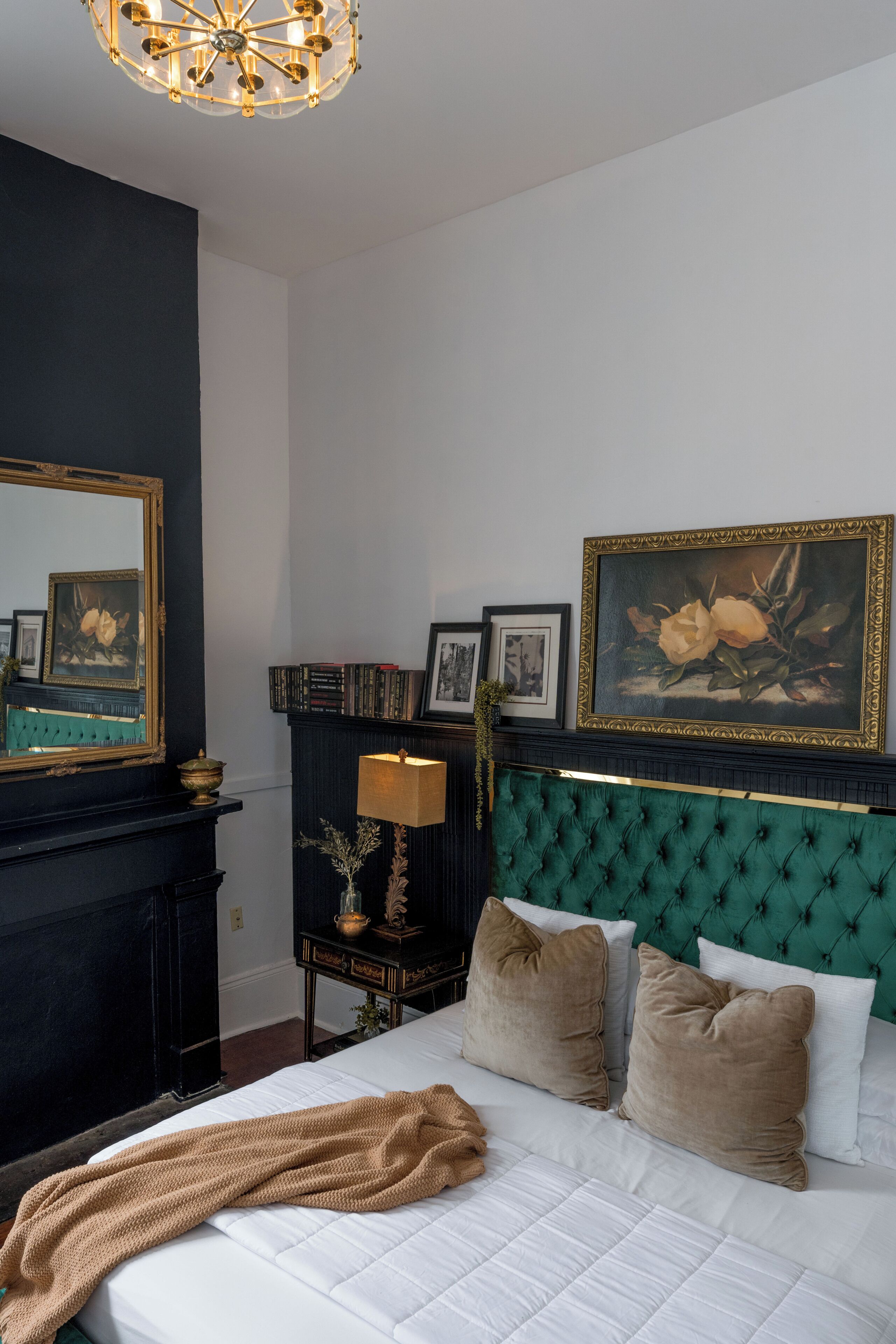 A bedroom with a large bed, a dresser, a mirror, and a wall with framed pictures.