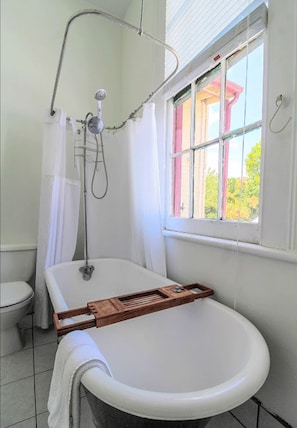 A bathroom with a bathtub, a shower, and a window. - The Mansion on Royal (New Orleans)