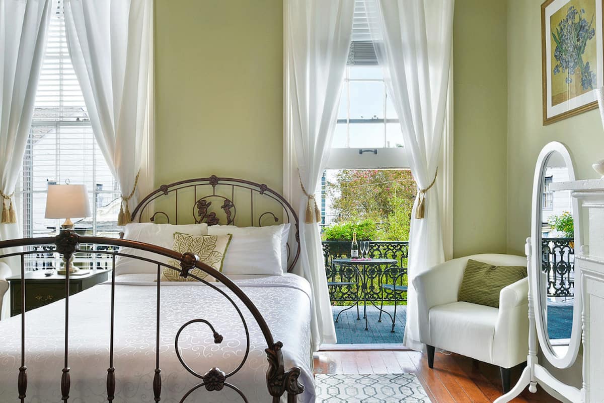 Une chambre à coucher comprenant un lit, une table de chevet, une chaise, une commode et un balcon avec vue.