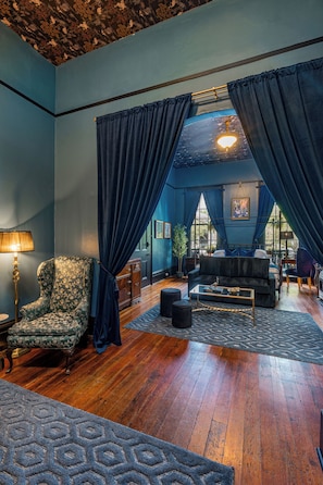 Una habitación con una decoración azul, que incluye un sofá, sillones, una lámpara y una alfombra estampada.