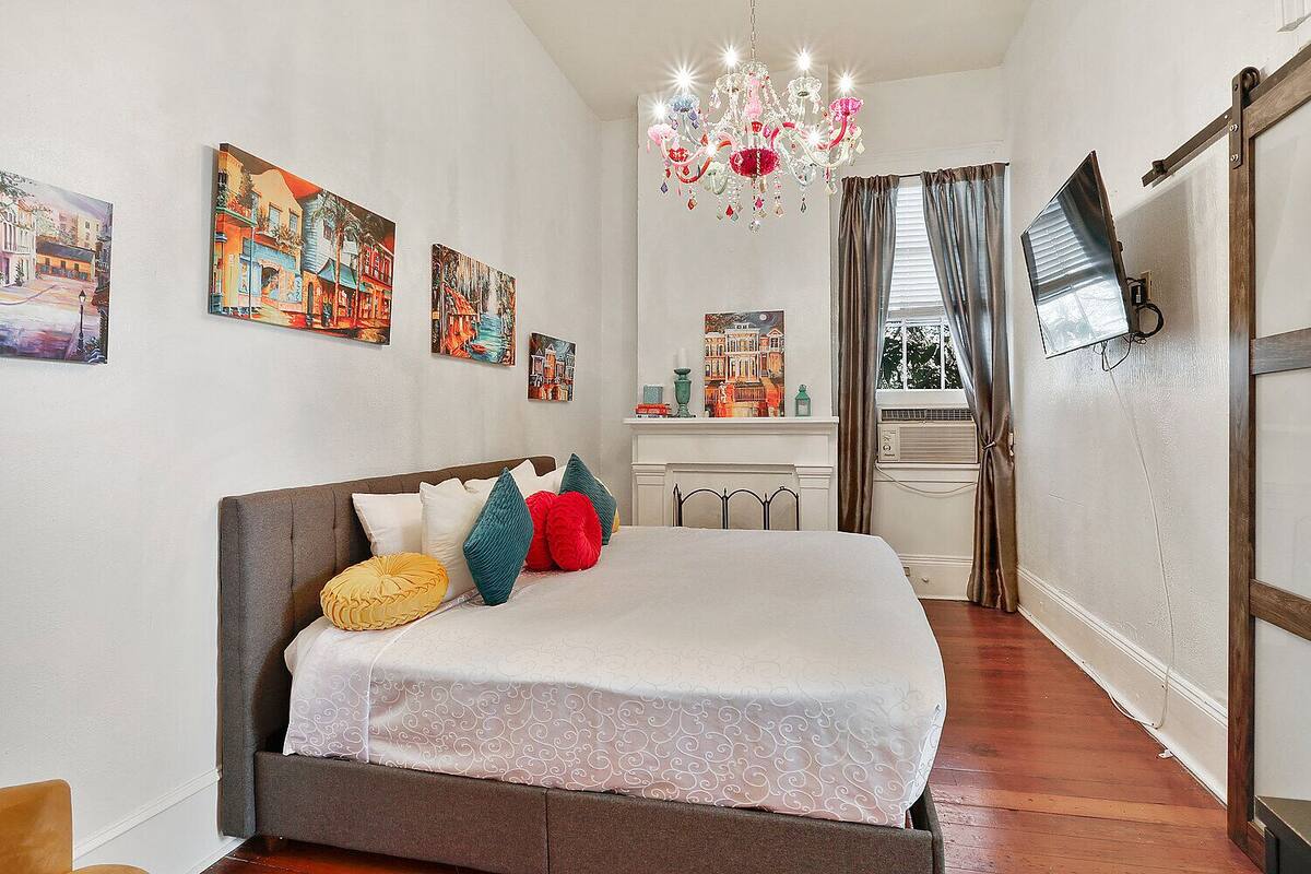 Une chambre à coucher avec un grand lit, un lustre et des œuvres d’art accrochées aux murs.