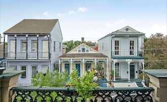 A row of three-story buildings with balconies, a central building with a porch, and a green railing in the foreground.
