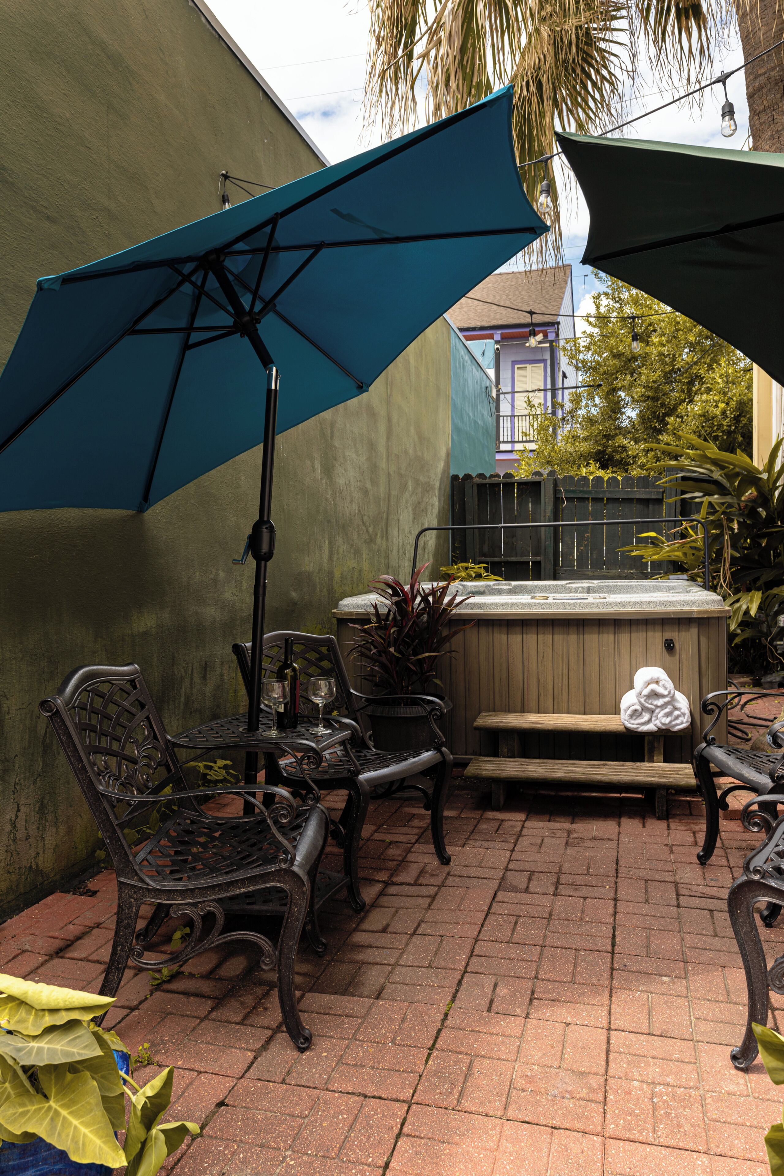 Eine Terrassenfläche mit Gartenmöbeln, darunter Stühle und ein Tisch, unter einem großen Sonnenschirm.