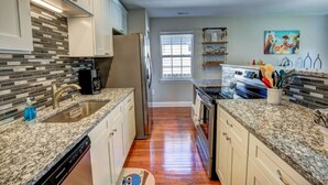 A modern kitchen with granite countertops, stainless steel appliances, and a tiled backsplash. - Cozy Cottage 3 beds 2 baths W/ Outdoor grill! (North Beach)