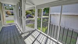 A covered porch with a view of a street and parked cars. - Cozy Cottage 3 beds 2 baths W/ Outdoor grill! (North Beach)