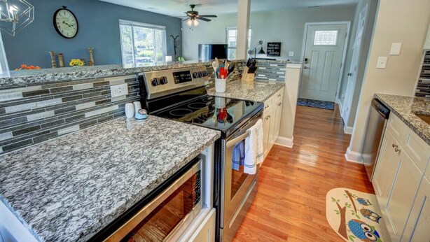 A kitchen with granite countertops, a stove, oven, and a ceiling fan. - Cozy Cottage 3 beds 2 baths W/ Outdoor grill! (North Beach)