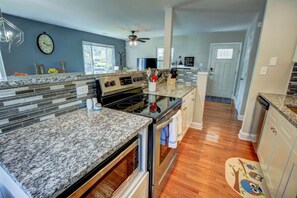 A kitchen with granite countertops, a stove, oven, and a ceiling fan. - Cozy Cottage 3 beds 2 baths W/ Outdoor grill! (North Beach)
