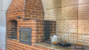 Un horno de ladrillo con una chimenea, un muro de azulejos y una olla sobre la encimera.