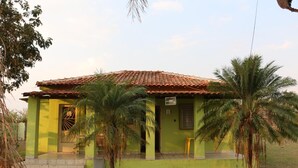 Una casa de un piso con techo de tejas, un porche delantero y palmeras en el jardín.