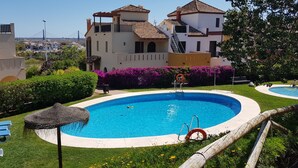 A swimming pool with a lifebuoy, lounge chairs, and a view of buildings in the background.
