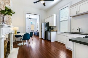 Una cocina moderna con armarios blancos, un refrigerador negro y una zona de comedor con sillas azules.